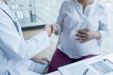 Doktor sağlığını kontrol ettikten sonra elini sıkar ve hamile kadınlara hamilelik tavsiyesi verir..