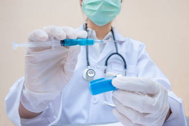 Doktorun elinde mavi bir aşı tüpü ve şırınga var..