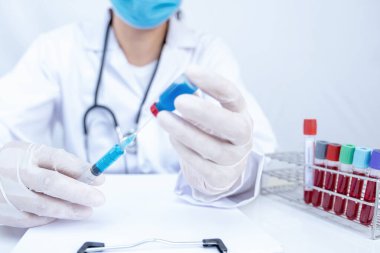 Doktorun elinde mavi bir serum tüpü ve şırınga var..