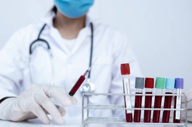 Kan tüpü ve doktorun elinde beyaz arka planda şırınga resmi..