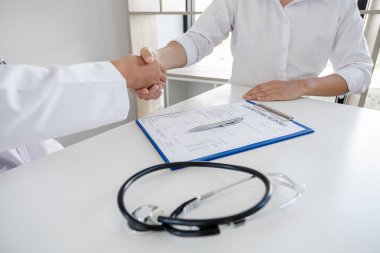 Doktorlar ve hastalar sağlık muayenesinin sonuçlarını öğrendikten sonra el sıkışıyorlar..