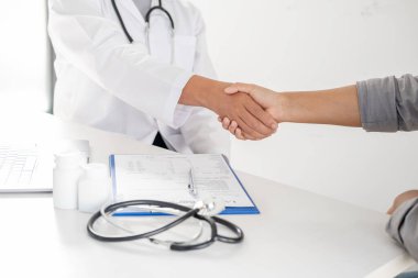 Doktorlar ve hastalar sağlık muayenesinin sonuçlarını öğrendikten sonra el sıkışıyorlar..