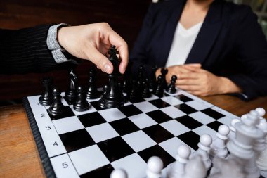 İş kadınları beyaz arka planda satranç oynuyor, iş stratejisini başarı konseptine taşımakta zorlanıyor.