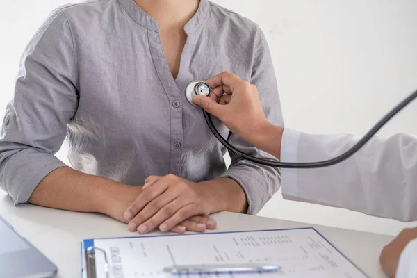 Doktor, hastayı steteskopla, tansiyon monitörüyle muayene eder ve sonuçları kaydeder..