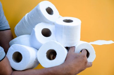Birkaç rulo tuvalet kağıdı tutan bir el resmi.