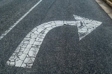 Sağa sadece beyaz ok, asfalta boyanmış, kırılmış ve dışarıdaki trafik yüzünden yıpranmış.