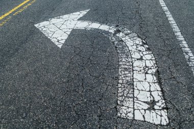Bir sola dönüş sadece beyaz bir ok asfalta boyanmış ve dışarıdaki trafik yüzünden yıpranmış.