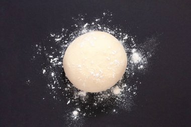 Yeast dough for making pizza bread against a dark background top view