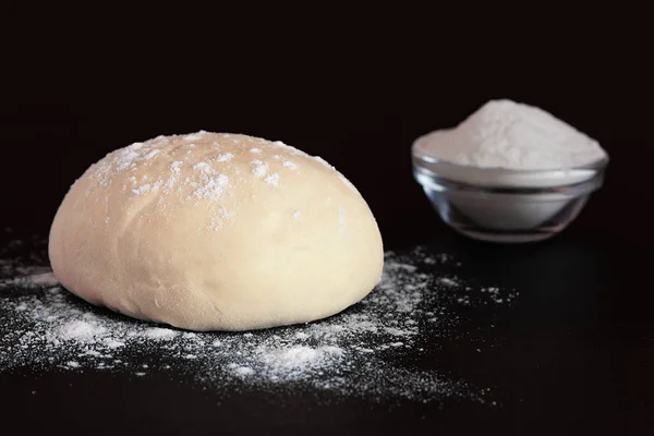 Pâte à levure et bol avec farine sur fond sombre — Photo