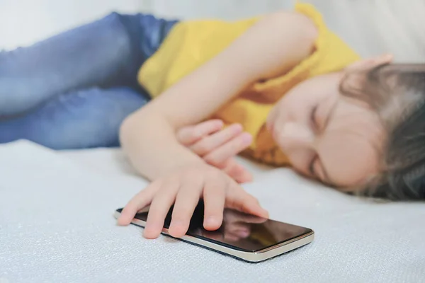 Dziewczyna śpi na kanapie trzymając iPhone w rękach — Zdjęcie stockowe