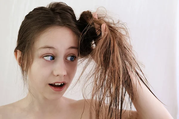 Nastolatka dziewczyna w niespodzianka patrzy na matowe włosy. — Zdjęcie stockowe
