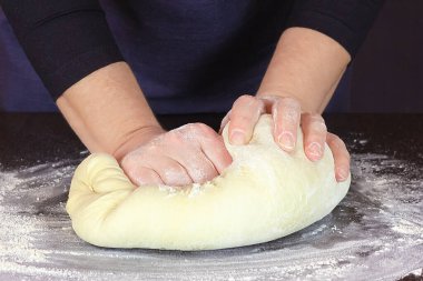 Kadın el şefi hamur yoğurur.