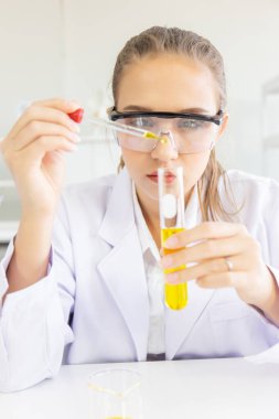 Güzel bir kadın bilim adamı laboratuvarda çeşitli ekipmanlarla çalışıyor..