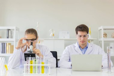 Sağlık araştırmacısı konsepti, yaşam bilimi laboratuvarında çalışan bir araştırmacı, genç bir araştırmacı ve bir erkek denetmen bir araştırma laboratuvarında mikroskobik slaytları hazırlayıp analiz ediyorlar.