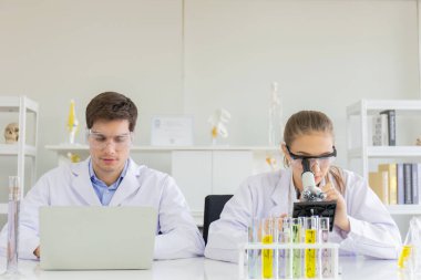 Sağlık araştırmacısı konsepti, yaşam bilimi laboratuvarında çalışan bir araştırmacı, genç bir araştırmacı ve bir erkek denetmen bir araştırma laboratuvarında mikroskobik slaytları hazırlayıp analiz ediyorlar.