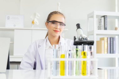 Güzel bir kadın bilim adamı laboratuvarda çeşitli ekipmanlarla çalışıyor..