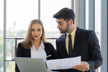 İki işadamı ve kadın takım elbise ve kravat giymişti. Ofisteki cam duvarın yanında duruyorlardı..