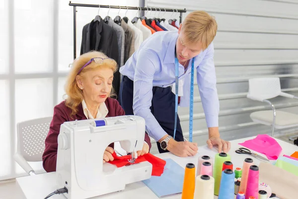 Professional team work designers, young men and elderly women in the office with a variety of fabric tones and equipment for various designs.