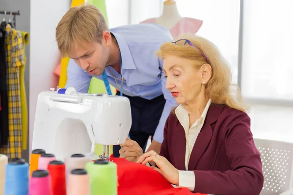 Professional team work designers, young men and elderly women in the office with a variety of fabric tones and equipment for various designs.