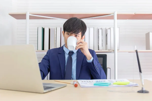若いアジアのビジネスマンが机の上にコーヒーを座っている — ストック写真