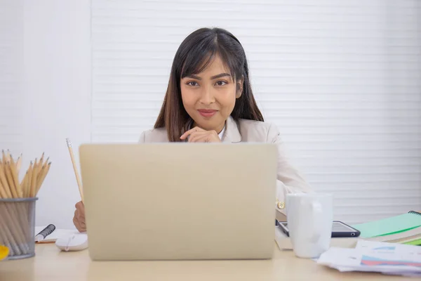 プロの若いアジアの実業家がオフィスの彼女の机に座っている — ストック写真