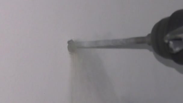 un homme perce un mur avec une perceuse 