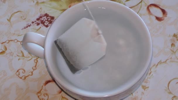 un sachet de thé est brassé dans une tasse d'eau bouillante 
