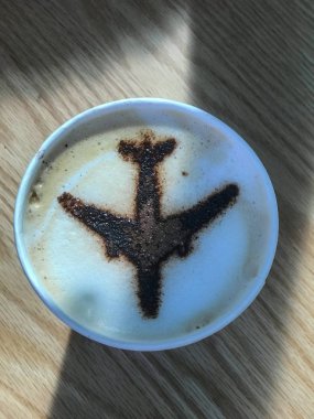 Pencereden yansıyan gölgesi olan köpük kapuçino üzerindeki bir uçağın karamel görüntüsü