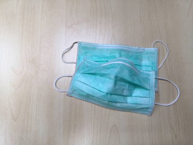 Yeşil yüz maskesi Covid 19 'u koruyabilir ama yüz maskesi ahşap masadan kalkar. Tehlikeli koronavirüs. Korunmak için tıbbi maskeler.