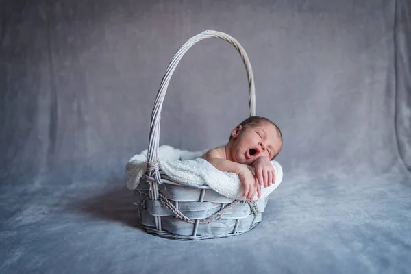 Ein neugeborenes Mädchen gähnt in einem Korb, während sie schläft. Gähnendes Konzept — Stockfoto