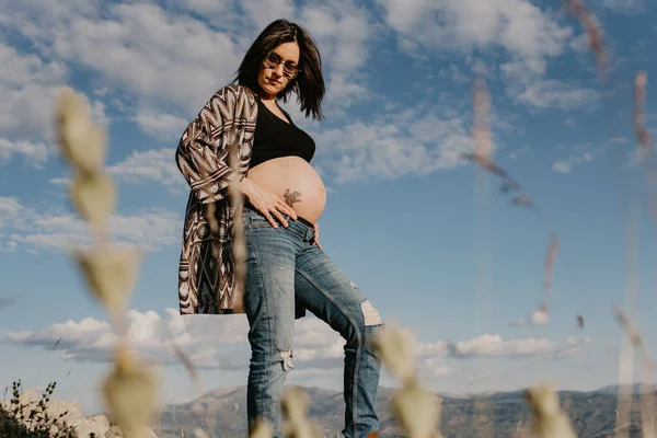 Ung gravid kvinna i naturen med bakgrund i berg och moln. konceptet session graviditet — Stockfoto