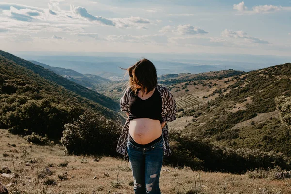 Ung gravid kvinna i naturen med bakgrund i berg och moln. konceptet session graviditet — Stockfoto