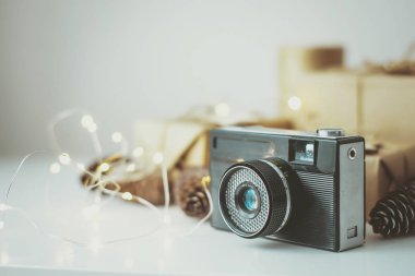 Beyaz masadaki Kraft kağıdında paketlenmiş hediyelerin arka planındaki retro kamera..