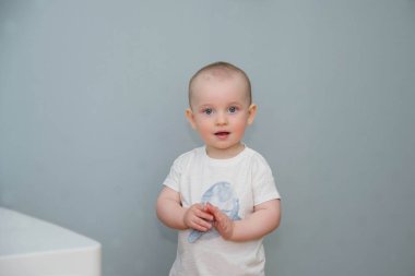 Mavi sırtında beyaz tişörtlü, mavi gözlü küçük bebek.