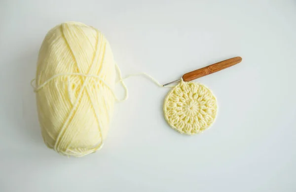 Светло-желтая пряжа для вязания на белом фоне и крючок — стоковое фото