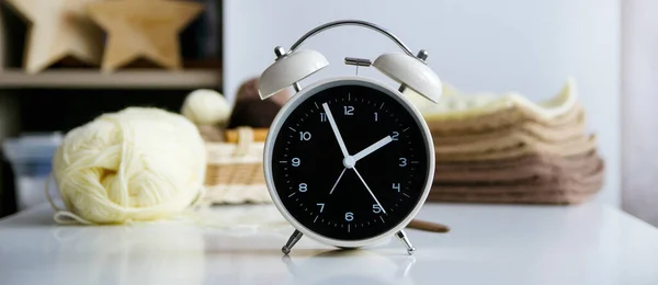 Clock alarm on a white table, on a knitting background. Concept — Stock Photo, Image