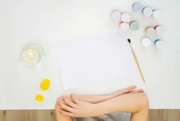 Top view on a white table, a sheet of paper, paints, brush, hand — Stock Photo, Image