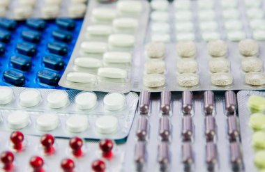 Haplar, ilaçlı kapsüller, pakette vitaminler, su toplayan paketler masanın üstünde..
