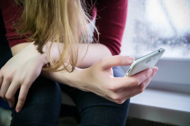 Yakın plan bir cep telefonu tutuyor. Bir cep telefonuna, internete, sosyal ağlara bağımlılık kavramı.