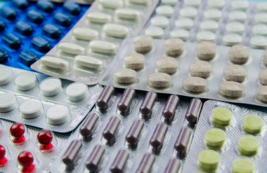 Haplar, ilaçlı kapsüller, pakette vitaminler, su toplayan paketler masanın üstünde..