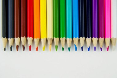 Beyaz arka planda üst üste renkli kalemler. Renkli kalemlerle pankart.