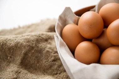 Tabakta tavuk yumurtası, bembeyaz bir masada keten peçete ve çuval bezi. Yumurtaları kapat..