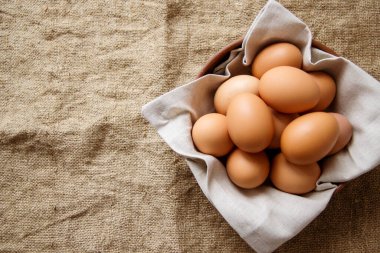 Çuval bezinden bir peçeteyle kilden tabakta tavuk yumurtası. Yukarıdan bak. Boşluğu kopyala.