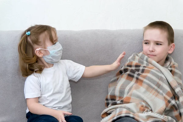 Keep a distance with sick people. A boy and a girl in a mask sit on a sofa in the distance and the girl pushes away the sick boy.