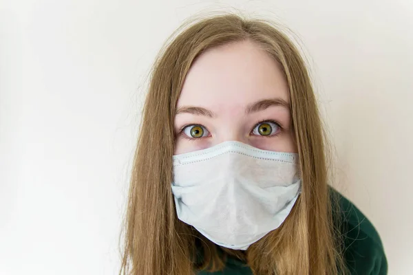 Girl in a medical mask closeup surprised, bulging, scared eyes.