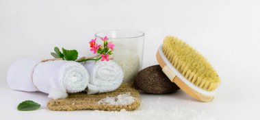 Beyaz arka planda havlular, sünger taşları, tuz ve mum ile spa tedavileri için hazır..