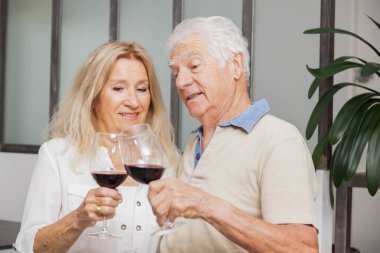 Mutlu son sınıf çifti evde mutfakta konuşurken ve kırmızı şarap içerken rahatlıyor.