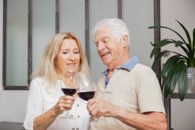 Mutlu son sınıf çifti evde mutfakta konuşurken ve kırmızı şarap içerken rahatlıyor.