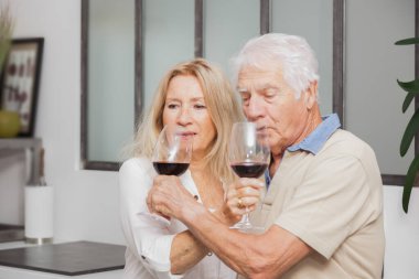 Mutlu son sınıf çifti evde mutfakta konuşurken ve kırmızı şarap içerken rahatlıyor.