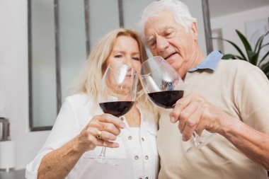 Mutlu son sınıf çifti evde mutfakta konuşurken ve kırmızı şarap içerken rahatlıyor.